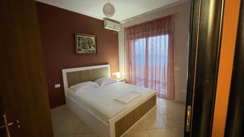 una camera da letto con un letto bianco e una finestra di Faro Apartment a Durrës