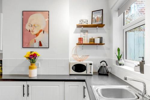 a white kitchen with a sink and a microwave at Stylish 2 bed city centre house in Norwich