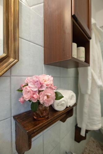 a vase of pink flowers on a wooden shelf in a bathroom at Agriturismo LaPievuccia in Castiglion Fiorentino