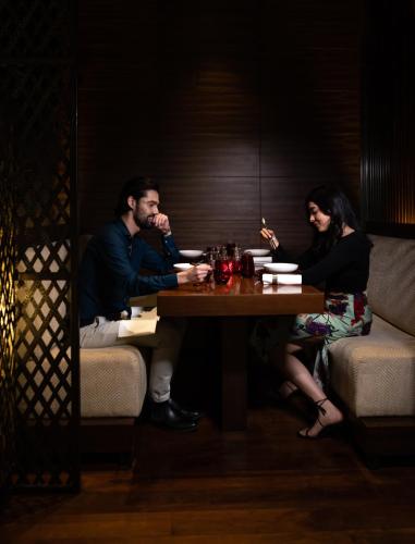 a man and woman sitting at a table in a restaurant at Grand Hyatt Mumbai Hotel and Residences in Mumbai