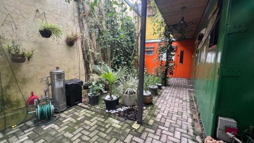 a courtyard with potted plants and a building with an orange door at Estúdios Conteiners de 02 a 04 hóspedes região lapa in Sao Paulo