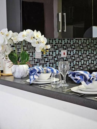 a counter top with plates and vases with white flowers at Luxury Botanica Studio Apartment 75 in Dubai