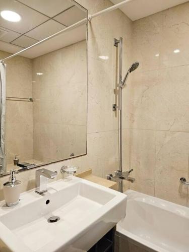 a white bathroom with a sink and a shower at Luxury Botanica Studio Apartment 75 in Dubai