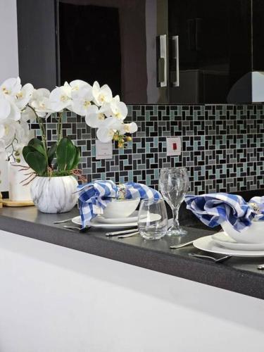 a counter top with plates and vases with white flowers at Luxury Botanica Studio Apartment 75 in Dubai