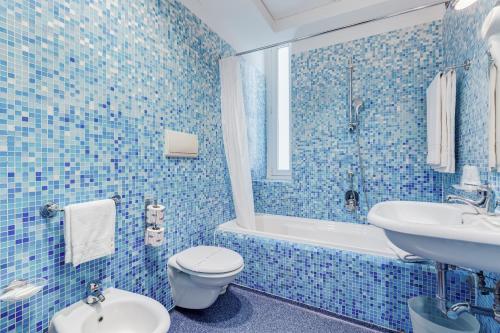 a blue tiled bathroom with a toilet and a sink at Best Western Plus Hotel Plaza in Naples