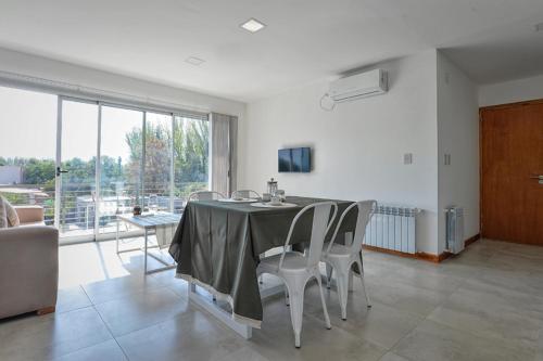 comedor con mesa y sillas y ventana grande en Preciosos departamentos en Ruta del Vino, zona de viñedos y bodegas en Luján de Cuyo