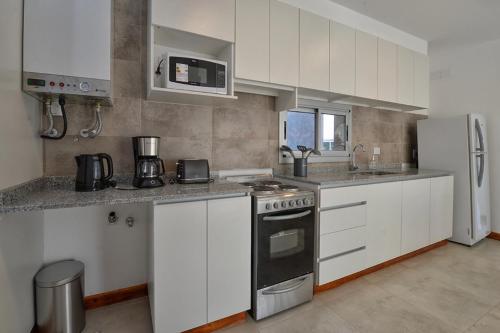 a kitchen with white cabinets and a stove top oven at Precioso departamento en Ruta del Vino, zona de viñedos y bodegas in Ciudad Lujan de Cuyo