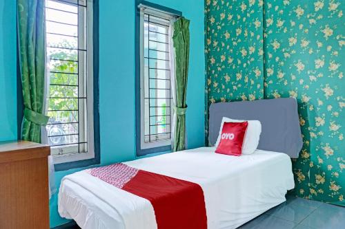Dormitorio azul con cama con almohada roja en OYO 91731 Home Stay Elis Cateliya Syariah, en Karawang