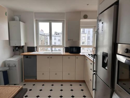 una cucina con armadietti bianchi e frigorifero di Jaurès-Pilier rouge/App spacieux/3 chambres/6 pers a Brest