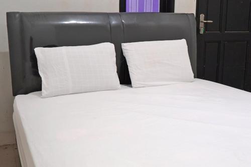 uma cama com duas almofadas brancas e uma cabeceira preta em OYO 92938 Kost Putih Syariah em Blitar