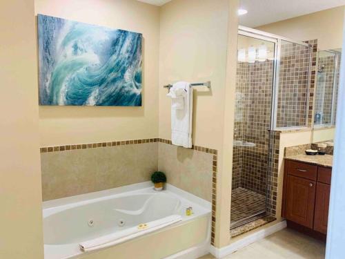 奧蘭多的住宿－Walking Distance from Universal One Bedroom Resort，带浴缸的浴室和墙上的绘画