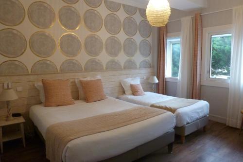 a bedroom with two beds and a wall with two windows at Family Golf Hotel in Royan
