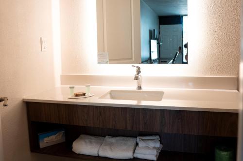 a bathroom with a sink and a mirror and towels at Howard Johnson by Wyndham Clearwater - Dunedin in Clearwater