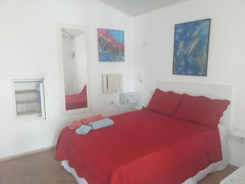 a bedroom with a red bed with paintings on the wall at Pousada Vila Magiosa in Búzios