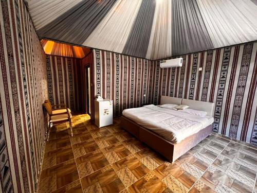 a bedroom with a bed and a chair in it at Tamim Luxury wadi rum camp in Wadi Rum