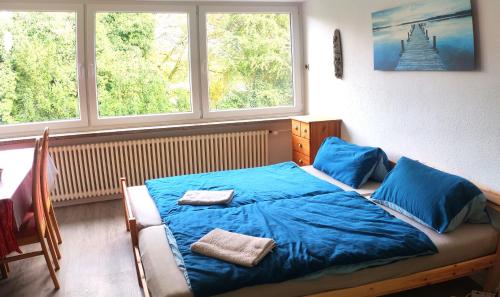 1 dormitorio con 1 cama azul y 2 toallas en Uni-nähes Apartmenthaus mit Garten, en Bochum