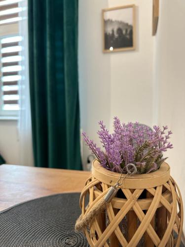 a basket with purple flowers in it on a table at Apartament Zielony Kołłątaja in Tomaszów Mazowiecki