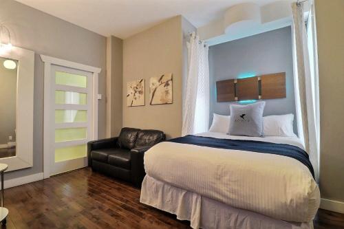 Un dormitorio con una cama y una silla de cuero negro en Château Queen by Bower Boutique Hotels, en Moncton