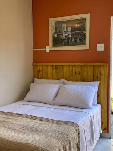 een bed in een slaapkamer met een oranje muur bij Aconchego Mineiro com Garagem in Belo Horizonte