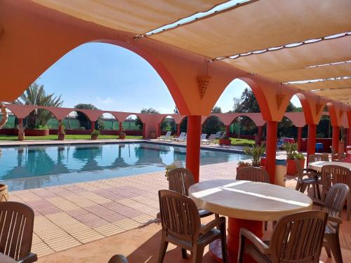 eine Terrasse mit einem Tisch und Stühlen neben einem Pool in der Unterkunft Chambre noura takat in Sidi Bibi