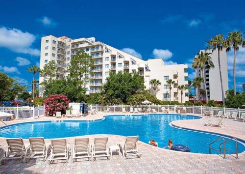 a swimming pool with chairs and a large building at Universal Studios. Amazing 2 bedroom apartment! in Orlando