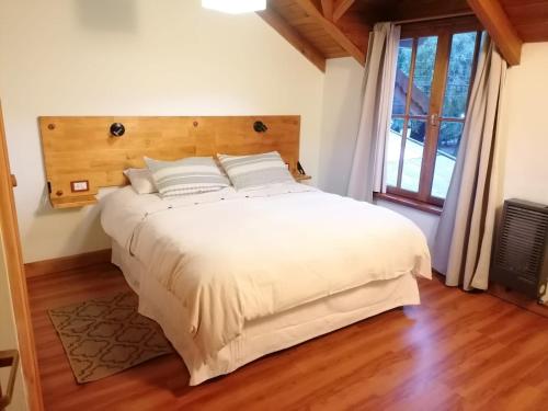 1 dormitorio con 1 cama blanca grande y cabecero de madera en Cálido departamento céntrico en San Martín de los Andes en San Martín de los Andes