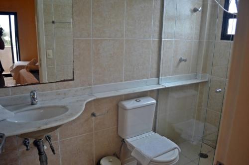 a bathroom with a toilet and a sink and a mirror at Hotel Canto do Atlântico in Guarujá