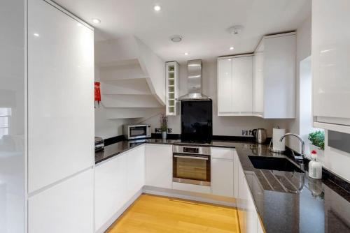 a kitchen with white cabinets and black counter tops at Fantastic 3-bed house with parking in Bath