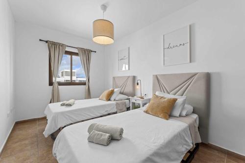 コスタ・テギセにあるHOLYHOME SunSplashの白い壁の客室内のベッド2台