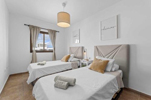 two beds in a room with white walls at HOLYHOME SunSplash in Costa Teguise