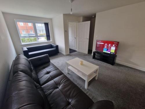 a living room with a leather couch and a tv at Comfy 3 bed home in Nottingham