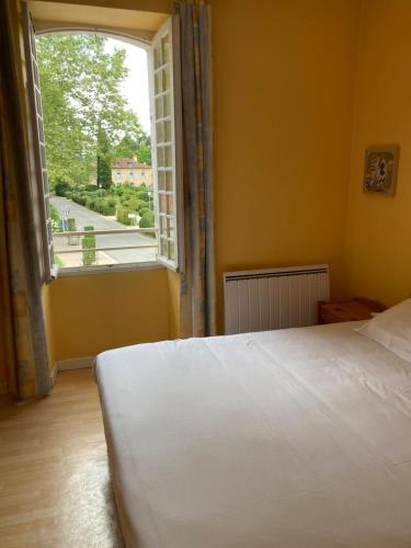 a bedroom with a white bed and a large window at Hôtel Chez Léonie - Chez Mamie Canne in Eugénie-les-Bains