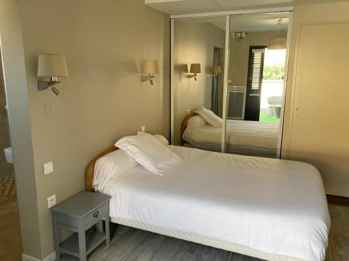 um quarto de hotel com uma cama e um espelho em Hôtel Chez Léonie - Chez Mamie Canne em Eugénie-les-Bains