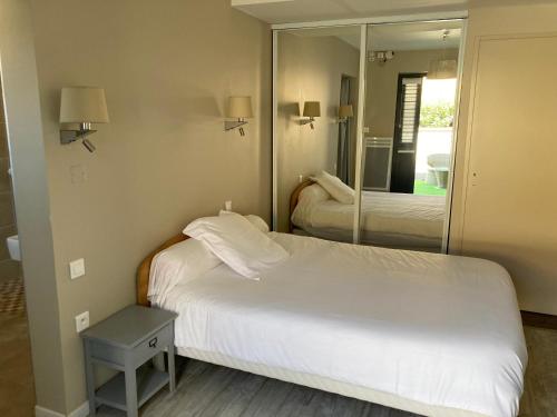 pokój hotelowy z łóżkiem i lustrem w obiekcie Hôtel Chez Léonie - Chez Mamie Canne w mieście Eugénie-les-Bains