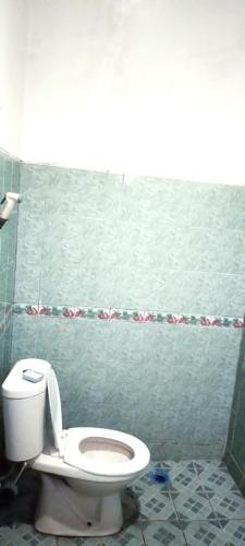 a bathroom with a toilet and a green wall at Berkah Huni , CIATER in Sarireja