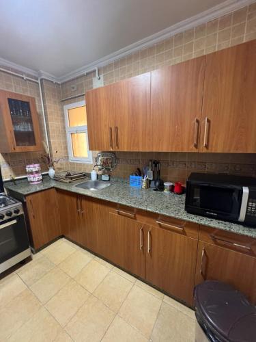 a kitchen with wooden cabinets and a microwave at Luxurious VIP Apartment in Madinaty Furnished with High End Hotel Furniture in Madinaty