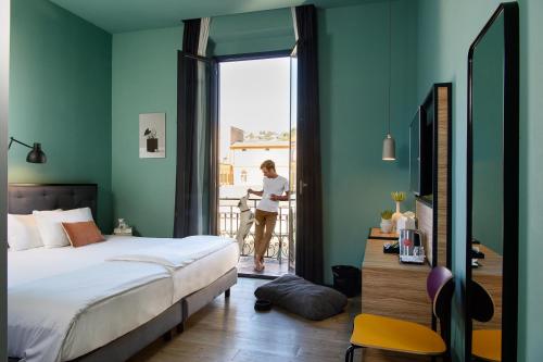 Una mujer parada en un balcón con vistas a la ventana de un dormitorio en The Poet Hotel, en La Spezia