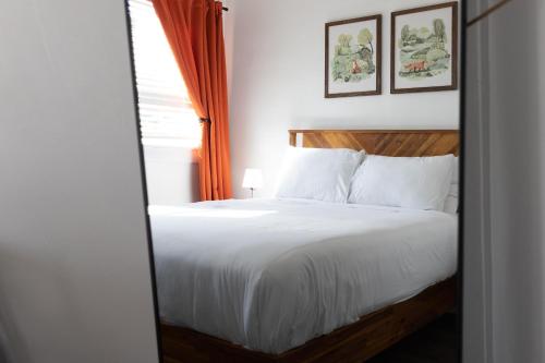 聖克勞德的住宿－亨特阿姆斯酒店，卧室配有白色的床和橙色窗帘