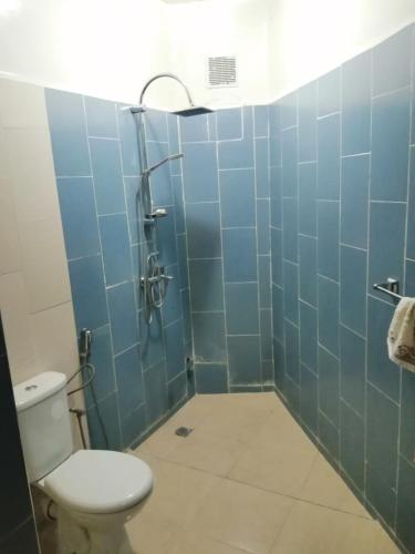 a bathroom with a toilet and a shower with blue tiles at Apartement bien équipé in Fez