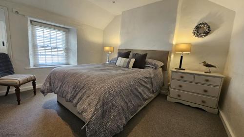 a bedroom with a bed and a dresser and a window at Beach Hill Cottage in Portloe