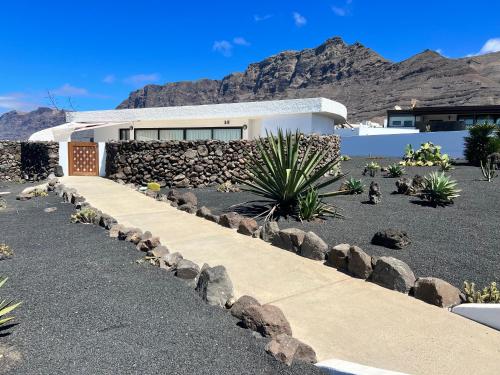 a house with a stone wall and a walkway at LANZAROTE FAMARA BEACH BUNGALOW in Famara