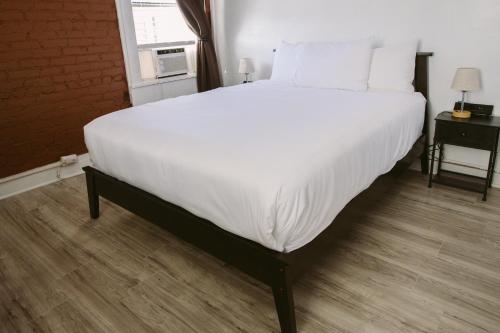 a large bed with white sheets and pillows in a room at Hunter Arms Hotel in Saint Cloud