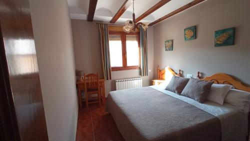 a bedroom with a bed and a window and a table at Casa Rural Lahuerta Apartamentos in Guadalaviar