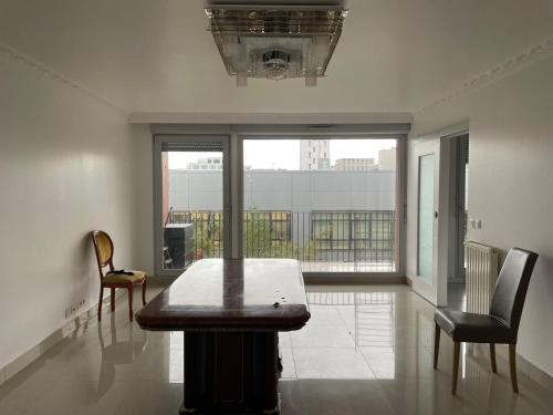 a room with a table and two chairs and a large window at Nuit Étoilée in Aubervilliers