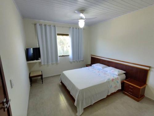 ein Schlafzimmer mit einem Bett und einem TV in der Unterkunft Casa de praia em Setiba in Guarapari