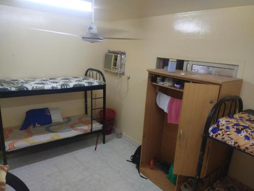 een kleine kamer met 2 stapelbedden en een bureau bij Bed space abu shagara park in Sharjah