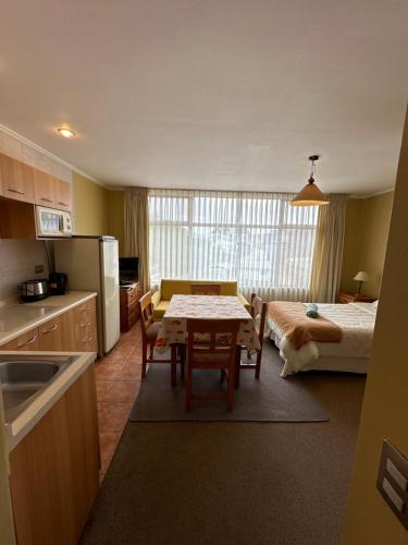 Una cocina con una mesa y una habitación con una cama. en Apart hotel Terra Valdivia, en Valdivia