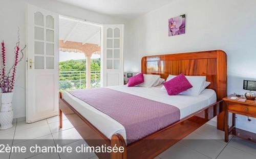 una camera da letto con un grande letto con cuscini viola di LA CANOPEE a Pointe-Noire