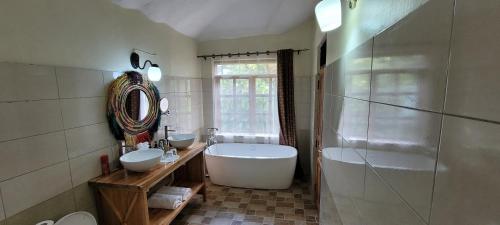 baño con 2 lavabos, bañera y ventana en Gorilla Safari Lodge, en Rubuguli
