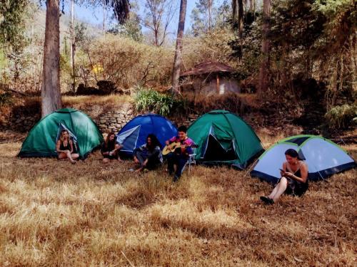 un gruppo di bambini seduti di fronte alle loro tende di Albergue Esmeralda - Camping a Sorata
